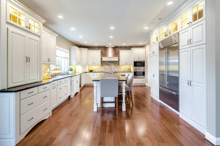 Spacious modern white kitchen featuring a large central island and hardwood flooring.
