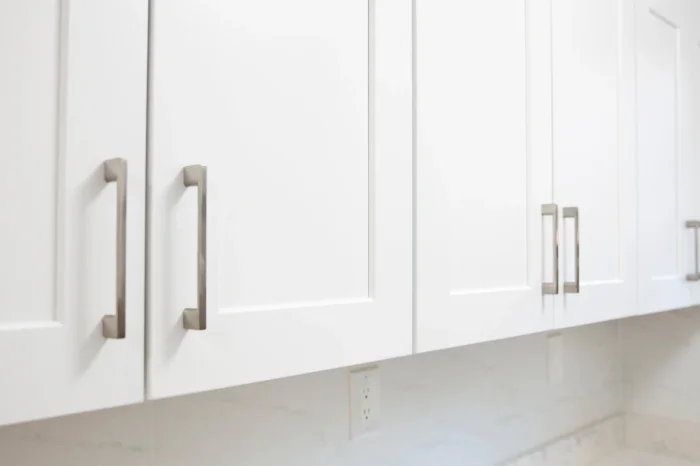Close-up view of white shaker cabinets with modern metal bars handles.