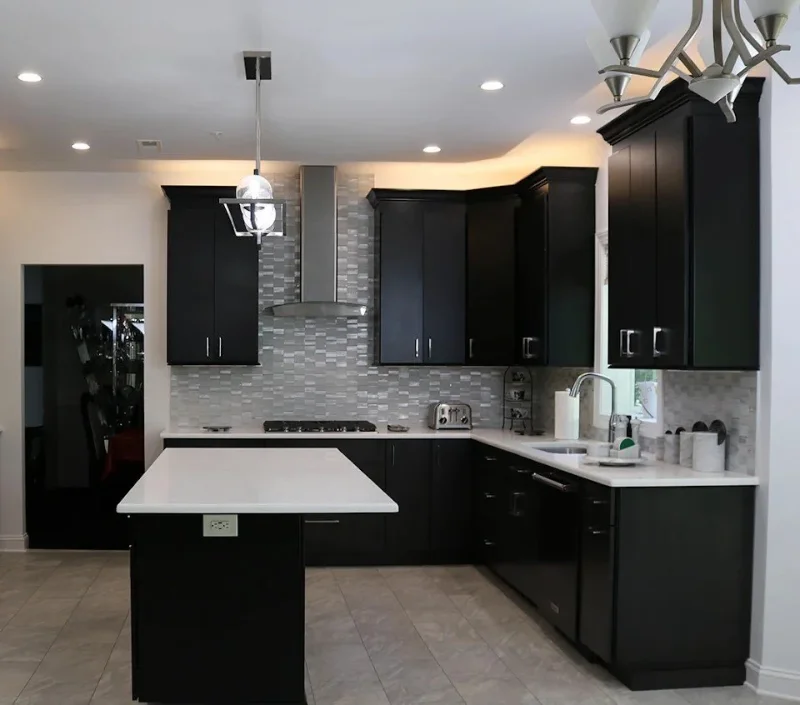 Contemporary kitchen design featuring minimalist black cabinets and a small white island.