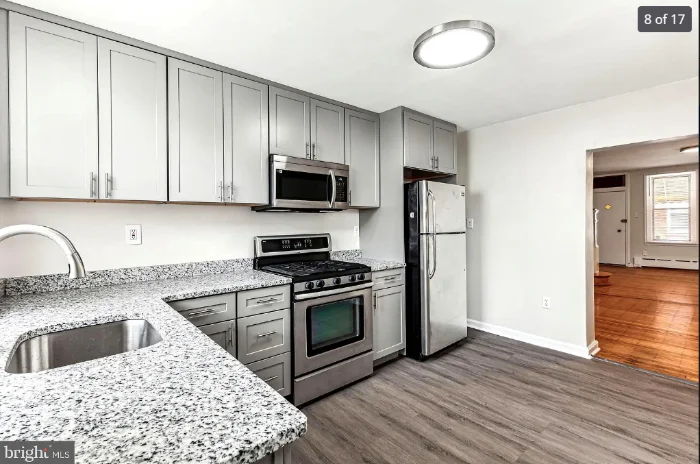 Contemporary kitchen design with light gray shaker cabinets, granite countertops, and stainless steel appliances.