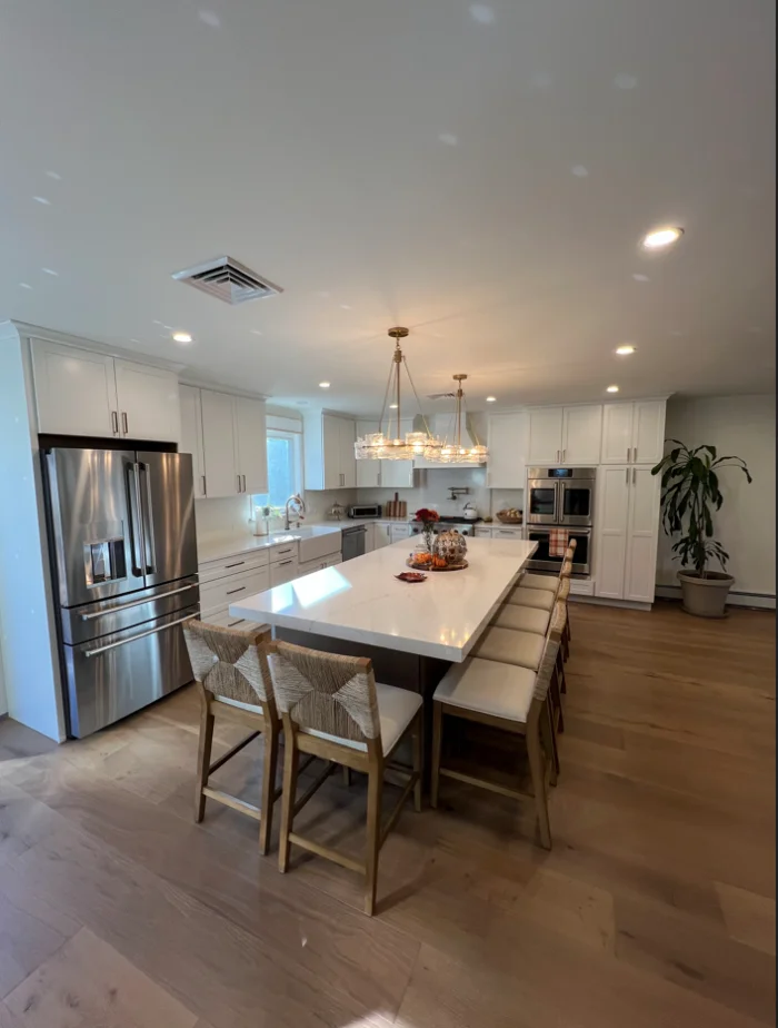 Spacious modern kitchen featuring white cabinets, a large island with barstools, and stainless steel appliances.