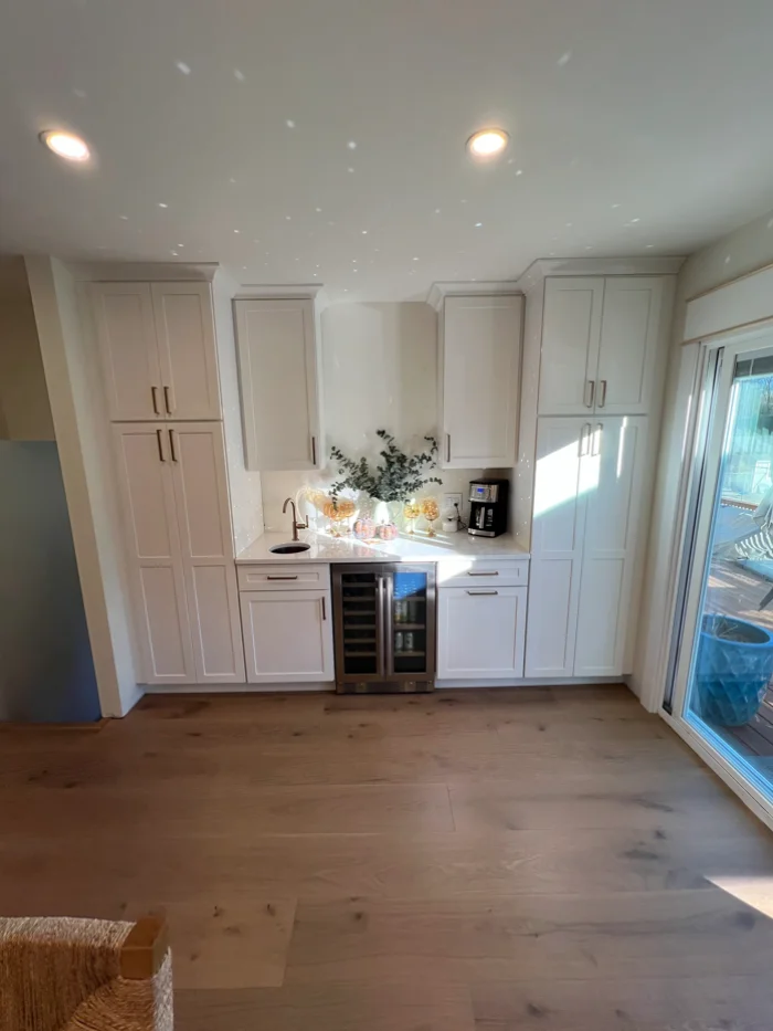 Clean kitchen accent wall featuring a white built-in pantry and wine fridge setup.