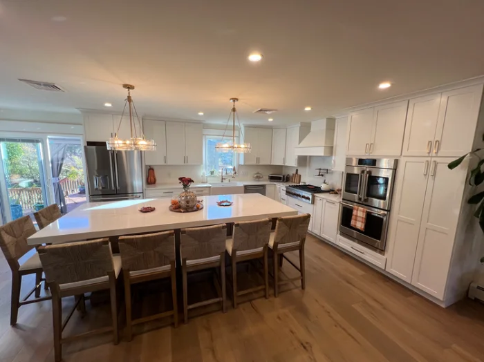 Large kitchen island with seating facing a wall of white perimeter cabinetry.