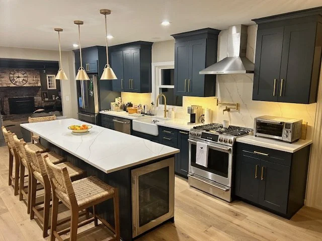 Deep blue kitchen cabinetry featuring gold hardware accents and a long central island.