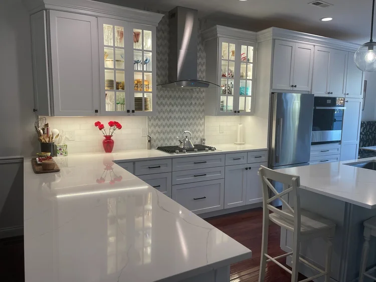 Modern white kitchen setup with custom illuminated glass front upper display cabinets.