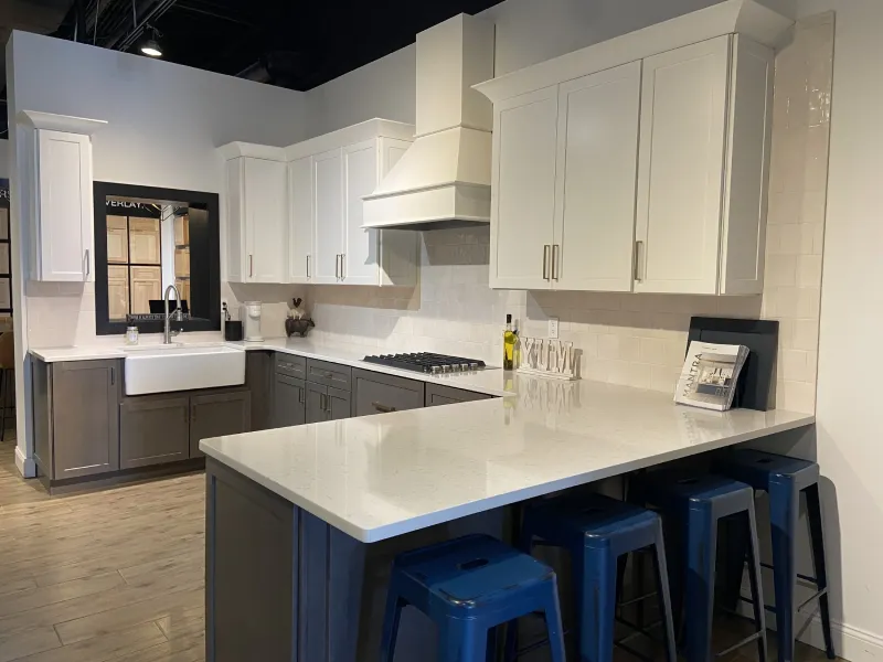 White farmhouse kitchen design highlighting an apron front sink and blue stools.