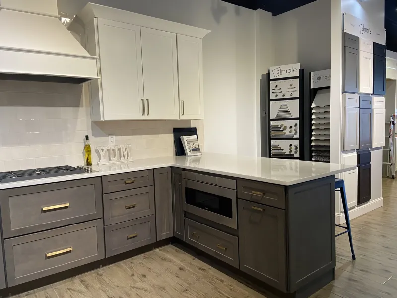 L-shaped kitchen display showing white upper cabinets and gray bottom drawer bases.