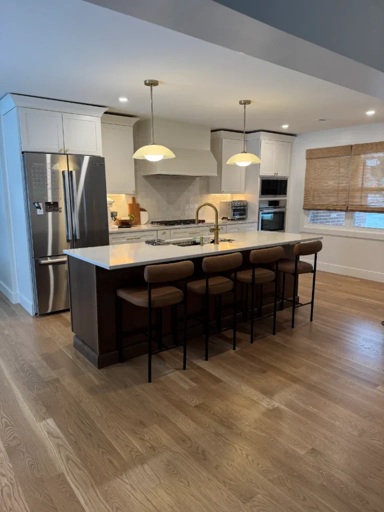 Open concept kitchen with a long dark wood island and pendant light fixtures.