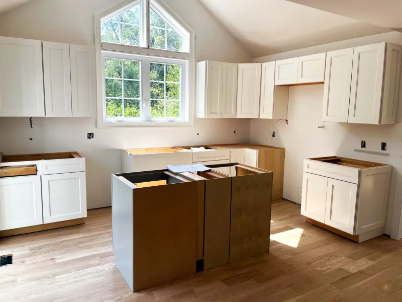 In-progress kitchen cabinet installation with white upper units.