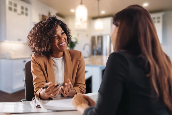 Two design professionals discussing paperwork at a kitchen table.