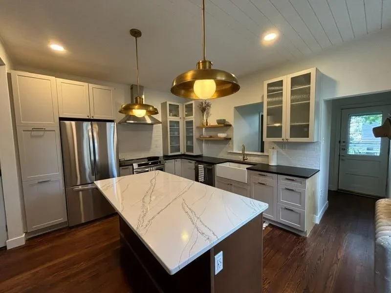 Cozy kitchen space highlighting a central island with a white quartz waterfall countertop.