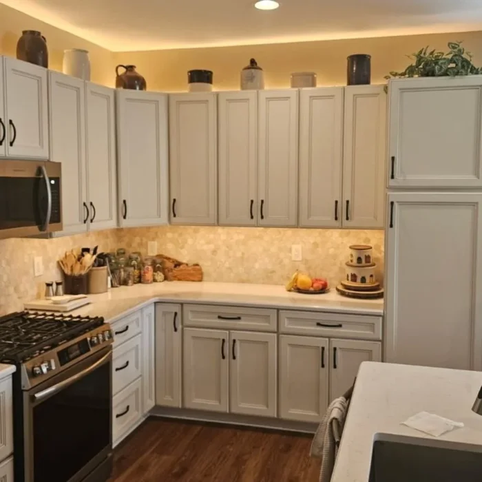 Warm kitchen area displaying off-white cabinetry with under-cabinet lighting and granite counters.