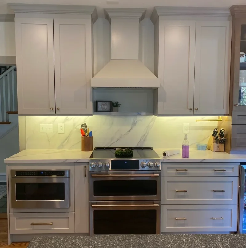 White kitchen stove area showcasing a matching wooden range hood cover shroud.