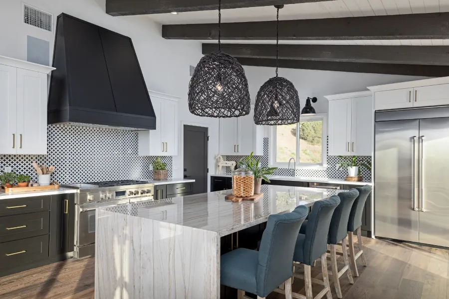 Modern kitchen featuring a large waterfall island with blue bar stools.