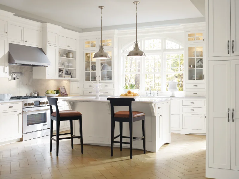 Bright white kitchen featuring a central island with two bar stools.