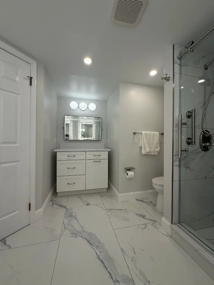 Modern bathroom with a white single-sink vanity and custom glass shower enclosure.