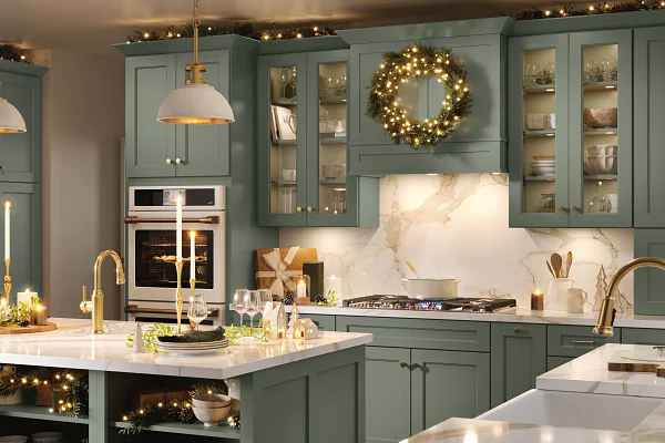 Elegant sage green kitchen cabinetry featuring illuminated glass doors and gold hardware.