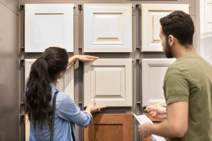 Couple choosing kitchen cabinet door styles from a showroom display.
