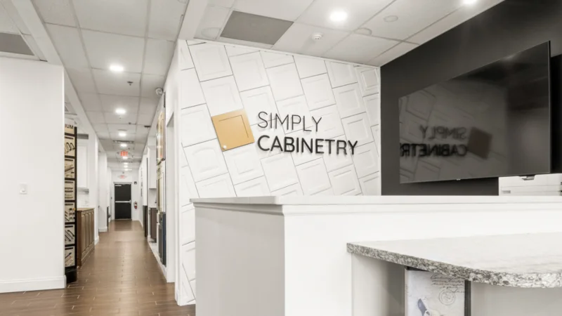 Modern office reception area featuring Simply Cabinetry signage on a textured wall.