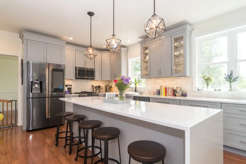 Modern light gray kitchen featuring a large central island with bar stools.