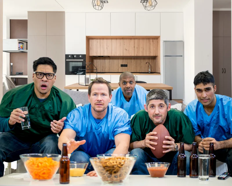 Group of friends watching a game on TV in a modern open plan kitchen.