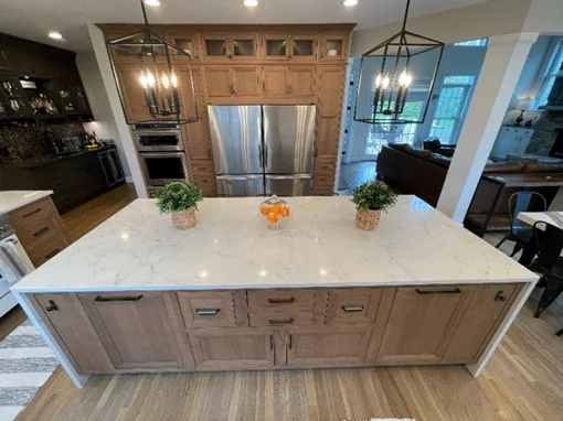 Spacious open concept kitchen highlighting a large natural wood island with quartz countertops.