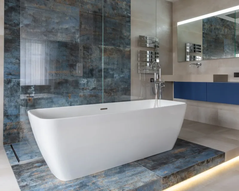 Modern bathroom featuring a standalone white bathtub on blue marble tiles.