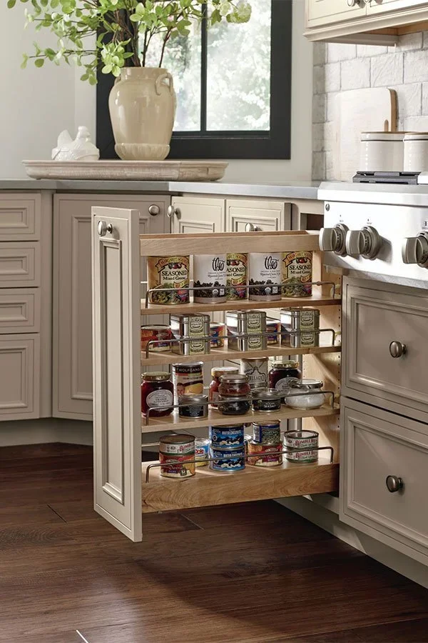 Pull out wooden spice rack cabinet organized with jars.