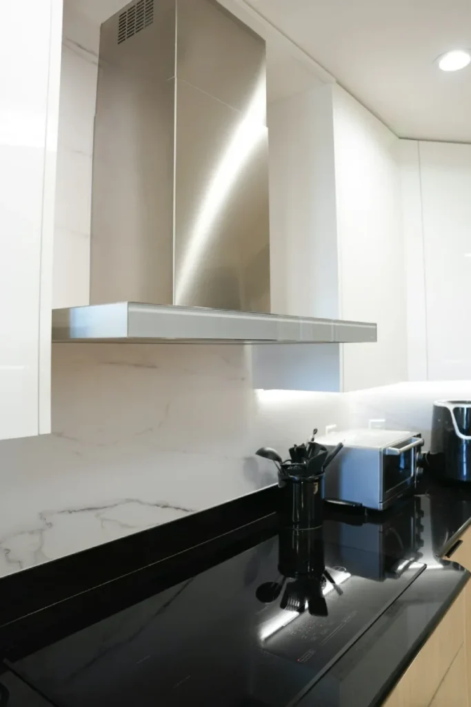 Stainless steel range hood mounted above a black glass stovetop.